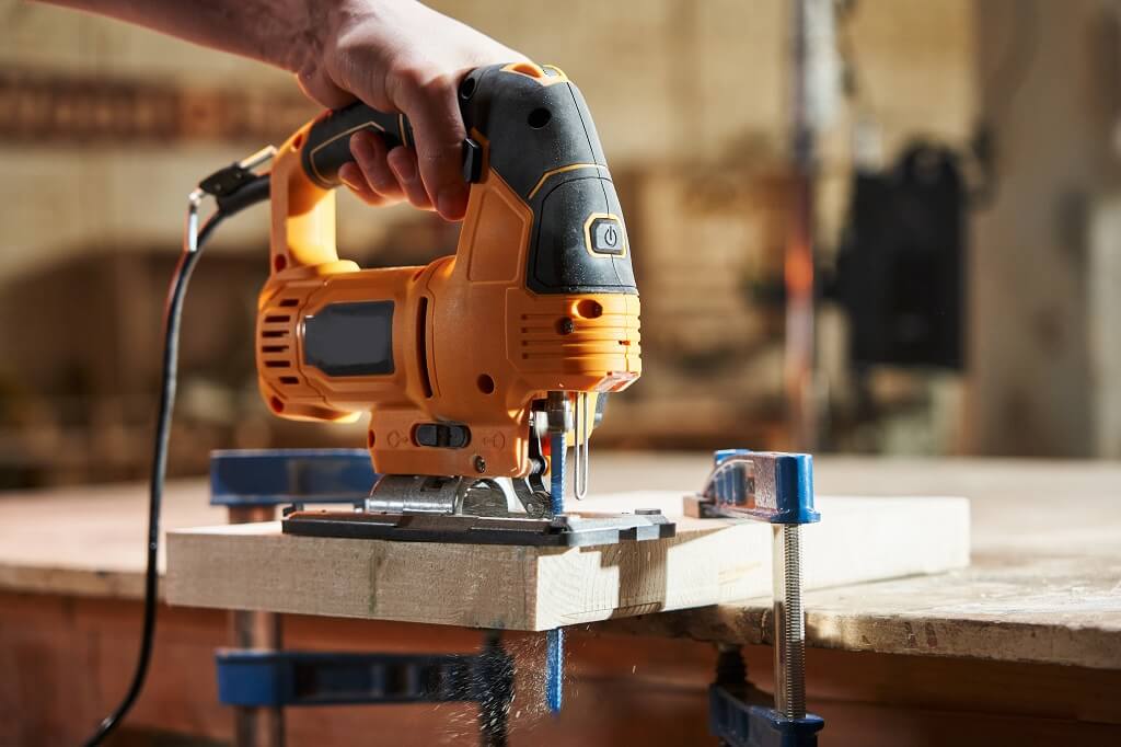 Električna ubodna testera tokom sečenja drveta na radnom stolu