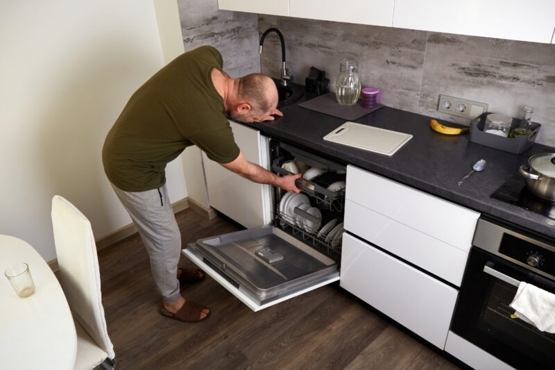 momak stavlja sudove u mašinu za sudove