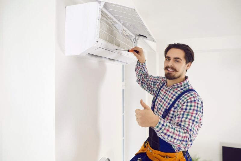 majstor zašraflja klima uređaj i pokazuje lajk palcem