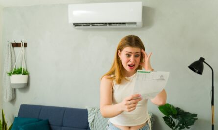 devojka se gleda u račun za struju i drži se za glavu sa otvorenim usnama, u pozadini klima uređaj na zidu
