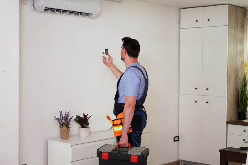 majstor proverava kako radi klima uređaj i drži kutiju alata u drugoj ruci